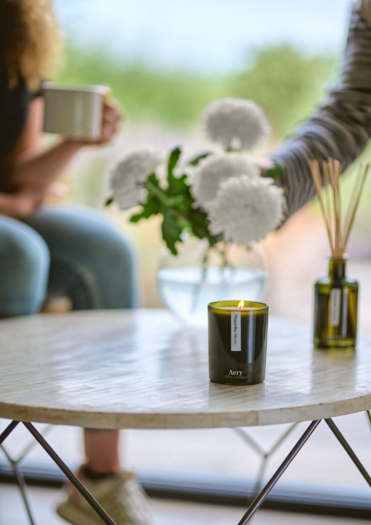Magnolia Blush scented candle by Aery displayed on circle table with diffuser