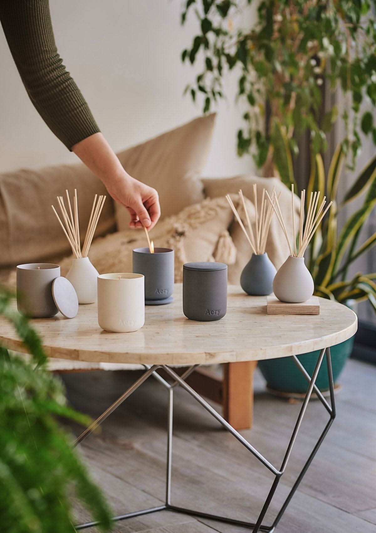 Nordic Cedar candle displayed next to fernweh candles and diffusers by Aery placed on cream circle table in kitchen