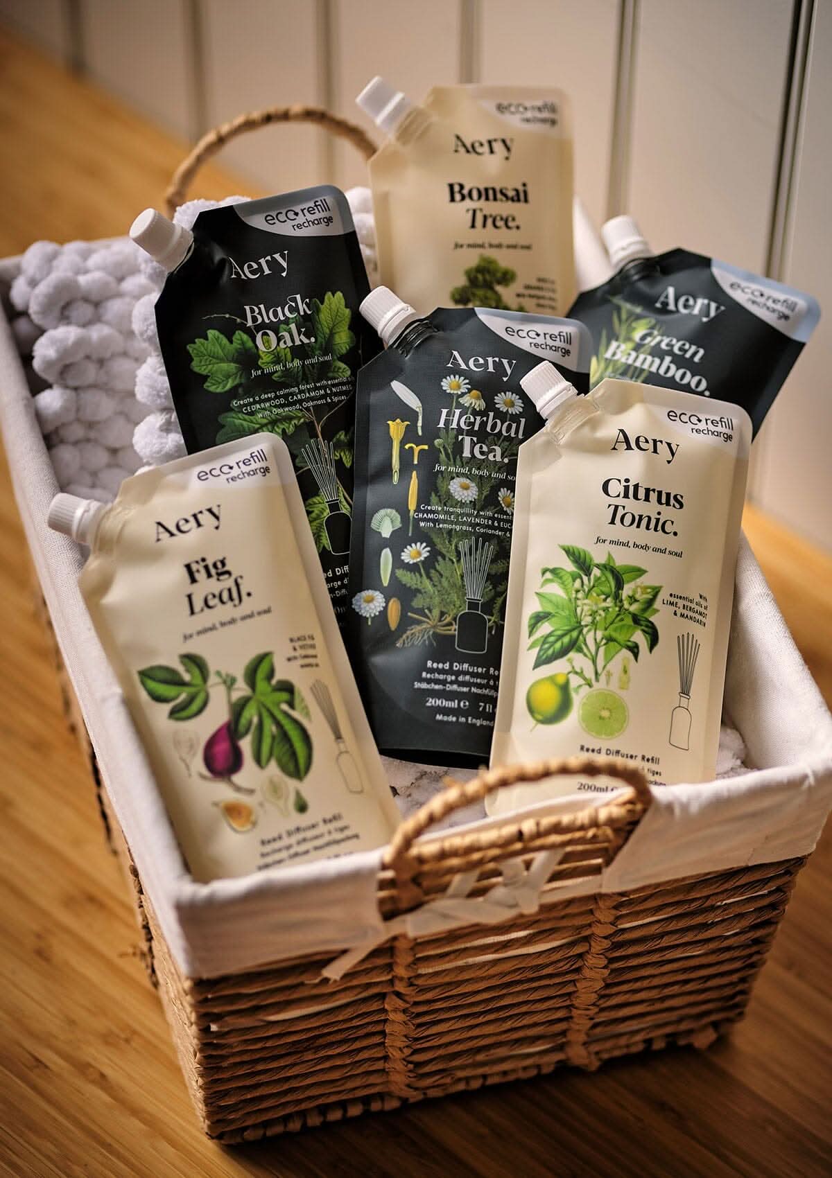 Collection of botanical reed diffuser refill pouches by aery placed wicker basket
