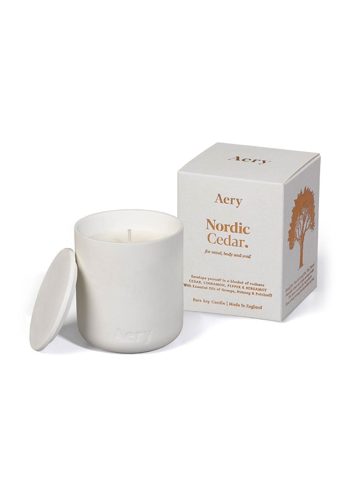 White Nordic Cedar ceramic scented candle displayed next to product packaging by Aery on white bacground 